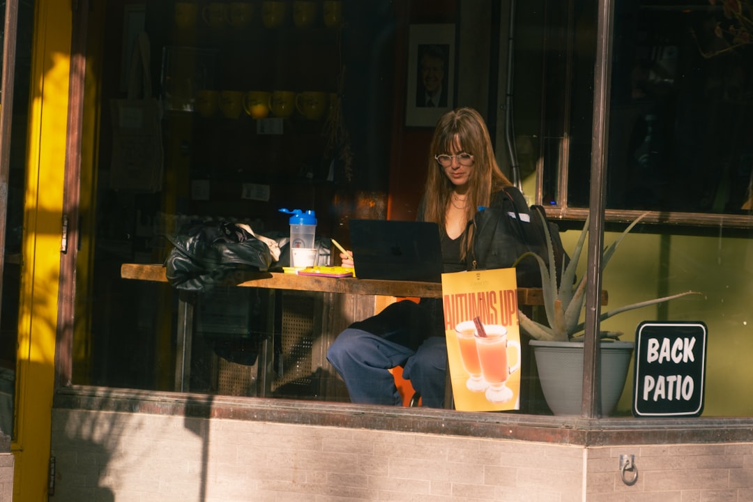 Woman working on laptop at outdoor cafe table.