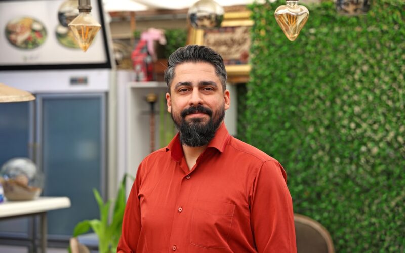 Man with beard in a red shirt smiling indoors