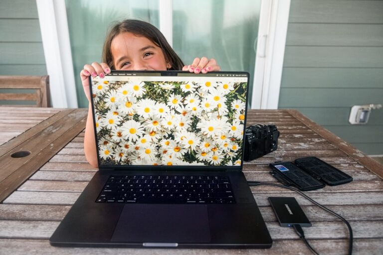 Girl peeking over laptop displaying daisies