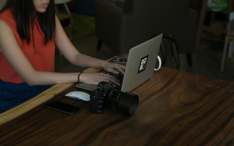 Woman typing on laptop with camera on table