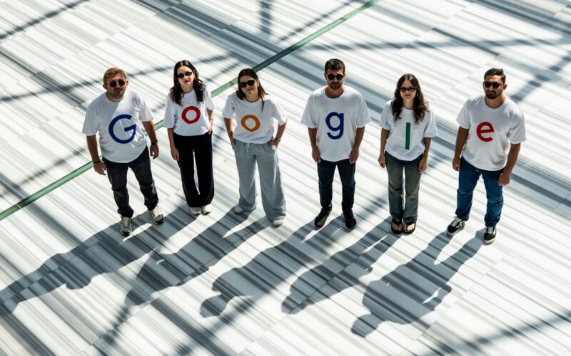 Six people wearing shirts spelling out google